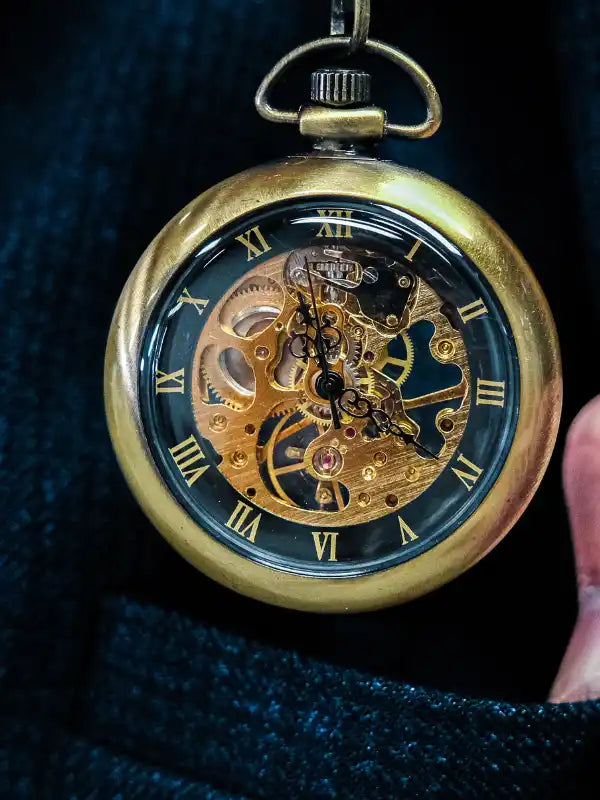 Aufwändige goldene Skeletttaschenuhr mit sichtbaren mechanischen Zahnrädern und römischen Zahlen.